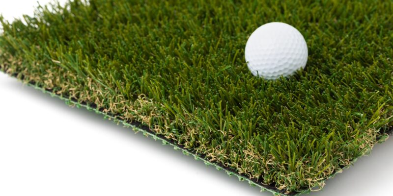 Golf Ball Resting on Section of Artificial Turf Grass On White Background