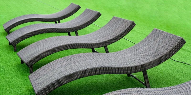 Modern black loungers on artificial lawn, ideal for poolside relaxation, showcasing premium outdoor furniture options.