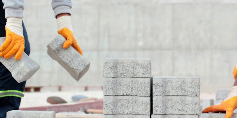 Paving stone worker is putting down pavers during a construction of a city street.