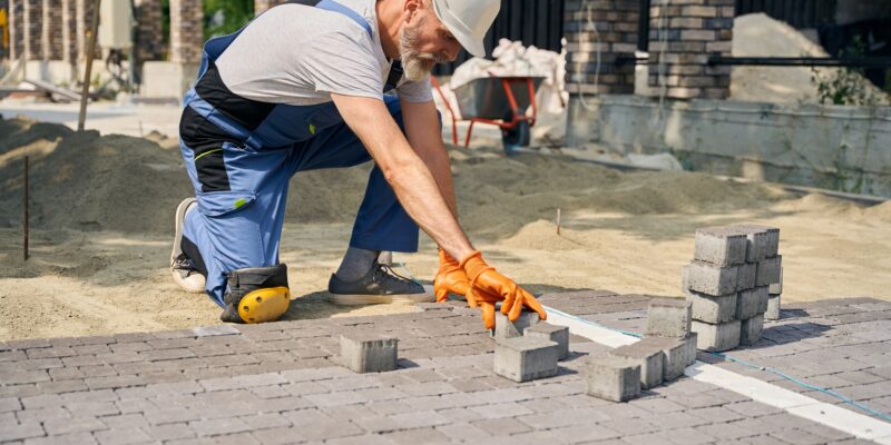 Skilled builder paving road on construction site